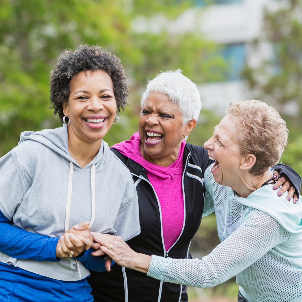 Three retired women laughing and embracing